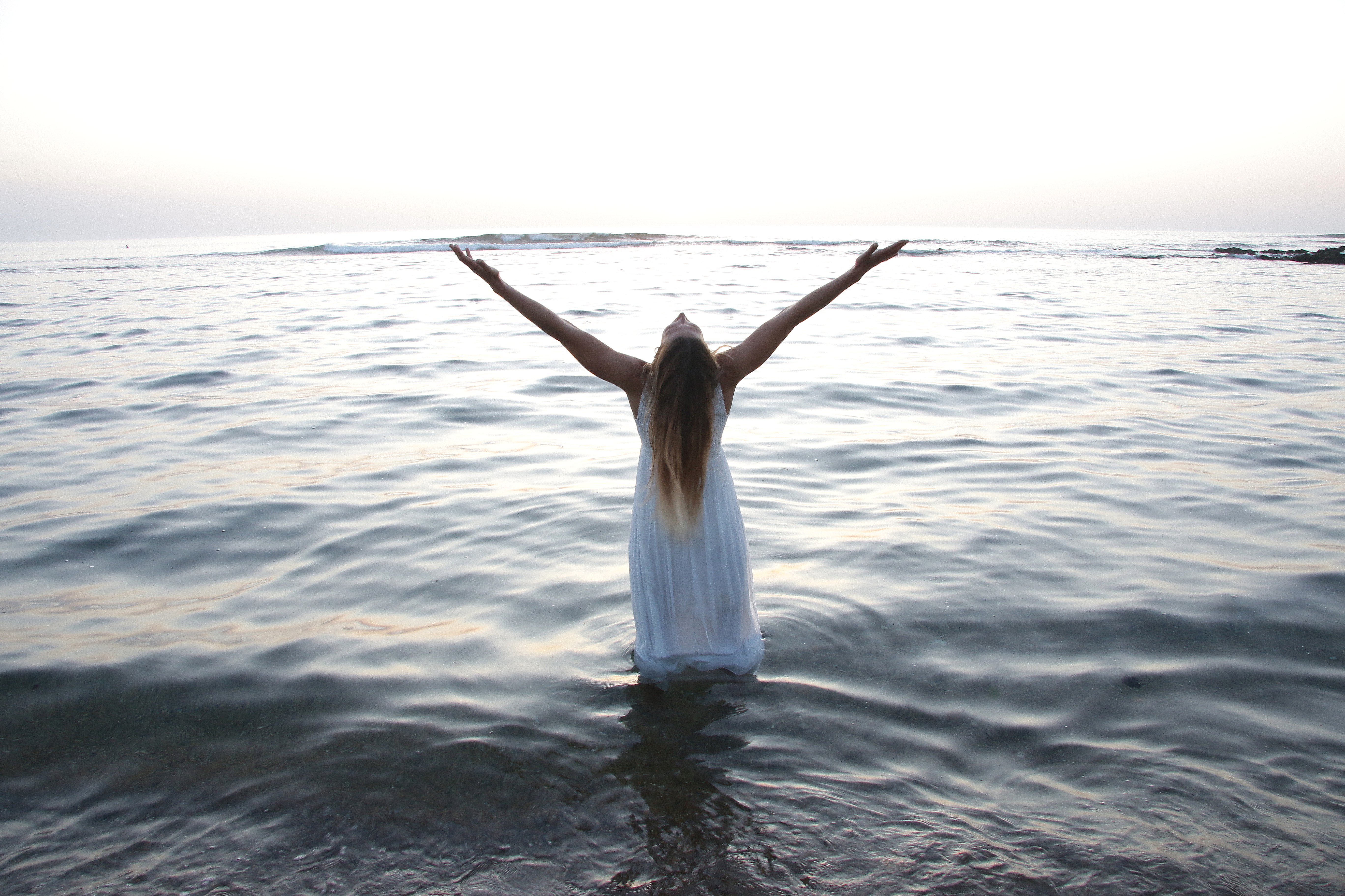 Femme dans l'océan à Saint-Jean-de-Luz, bras ouverts, guérison après psychotraumatisme de violences sexuelles, reconnexion au corps montrant libération, apaisement, sécurité et puissance