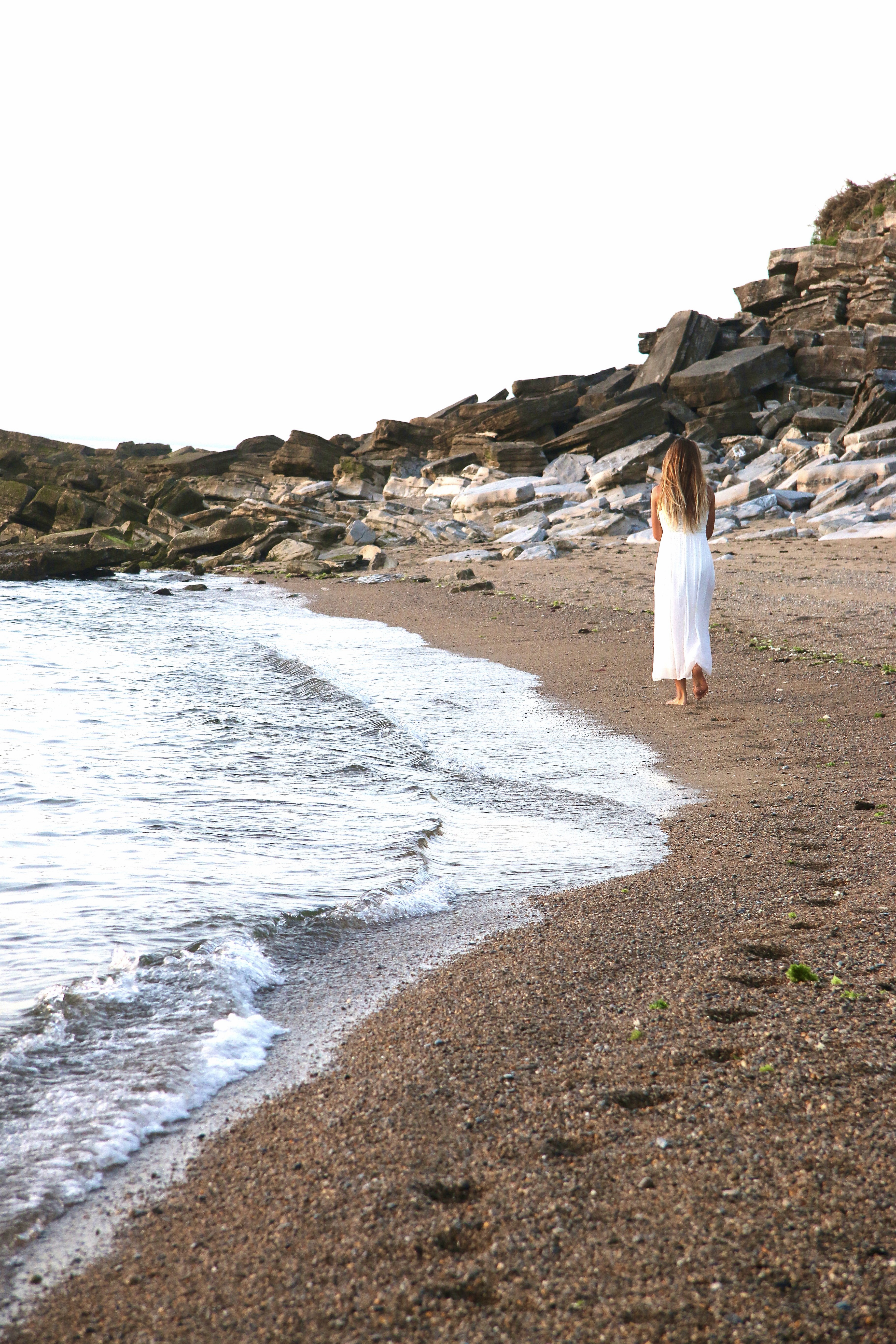 Femme marchant au bord de la mer sur une plage à Saint-Jean-de-Luz, Pays basque, symbole de reconstruction après libération de traumatisme et reconnexion au corps